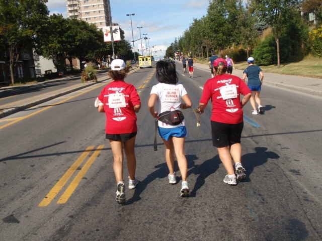 Two guide runners and visually impaired runner participating in a marathon